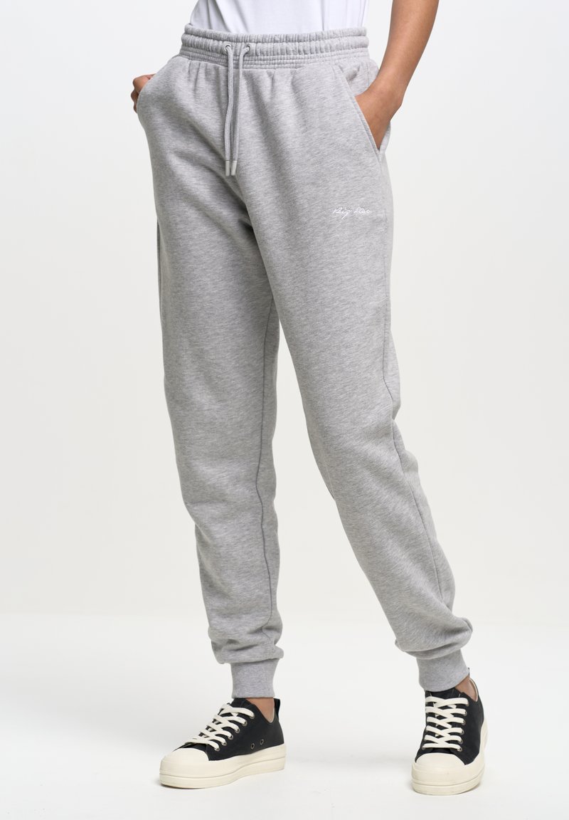 Hellgraue Baumwoll-Sweatpants mit elastischem Bund, seitlichen Taschen und gerippten Bündchen. Mit dezenten weißen Branding auf dem Oberschenkel.