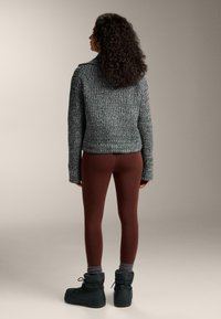 Šedý pletený svetr s vysokým límcem, doplněný bordó legínami a černými kotníkovými botami. Svetr má texturovaný vzor.