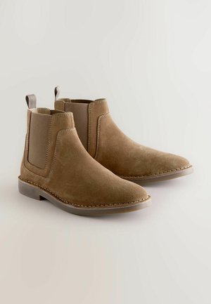 Tan suede Chelsea-saappaat, joissa on elastiset sivupaneelit, pyöristetty kärki, ommeltuja yksityiskohtia ja vetotangot kantapäällä. Litteä kumipohja.