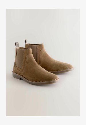 Tan suede Chelsea-saappaat, joissa on elastiset sivupaneelit, pyöristetty kärki, ommeltuja yksityiskohtia ja vetotangot kantapäällä. Litteä kumipohja.