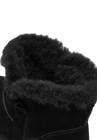 Čierne nubukové topánky s jemným, chlpatým čiernym podšívkou na okraji. Dizajn obsahuje zaoblený tvar s viditeľnými detailmi šitia.