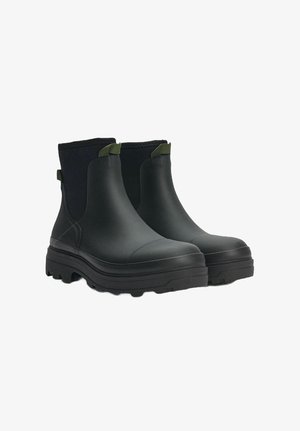 Black waterproof ankle boots with a smooth rubber finish, elastic side panels, and textured, rugged soles. Green pull tabs on the upper.