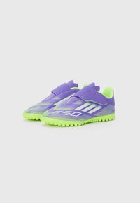 Chaussures de sport violettes et vertes avec une surface texturée, des bandes Velcro et une semelle structurée dotée de petits crampons pour l'adhérence.
