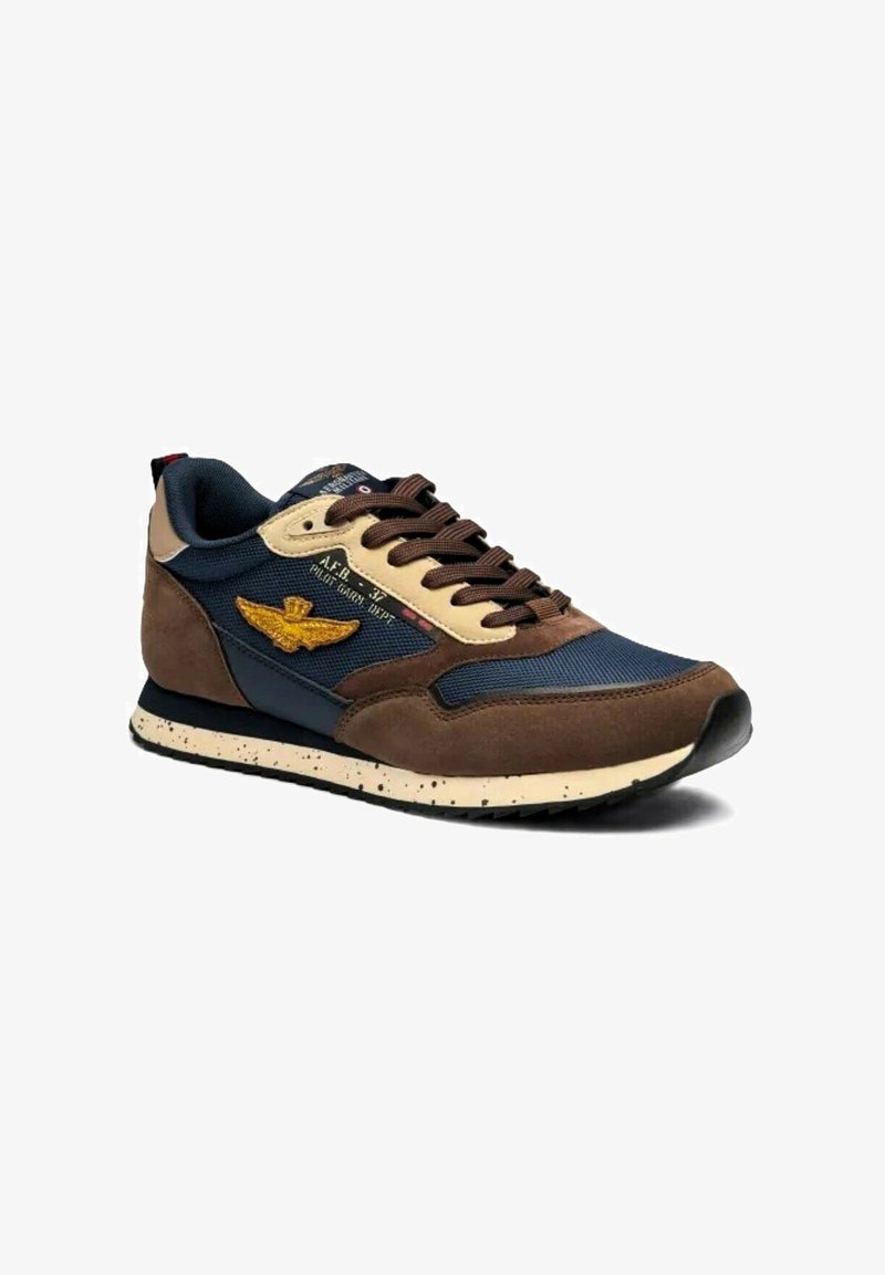 Sneaker marroni e blu navy con una tomaia in suede e rete, dettagli beige, suola in gomma e un emblema dorato a forma di ala sul lato.