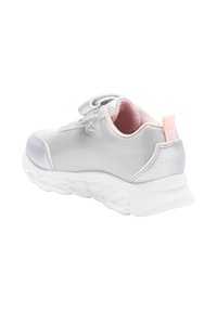 Sneakers sportive con una parte superiore argentata lucida, dettagli rosa, fodera in rete e una suola bianca texturizzata. Chiusura con strap per una facile calzata.
