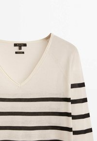 Pull en tricot crème avec un col en V, comportant de larges rayures noires horizontales, des détails côtelés et une texture douce.