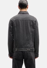 Schwarze Jeansjacke mit klassischem Kragen, Knopfakzenten und leicht ausgewaschener Textur. Verfügt über eine gerade Silhouette und markante Nähte.