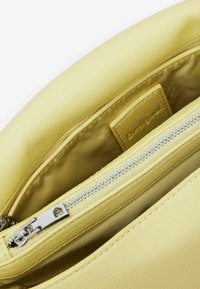 Borsa in pelle gialla con una superficie liscia, dotata di chiusura a zip e di un'etichetta interna. Il materiale della zip è di colore argentato.