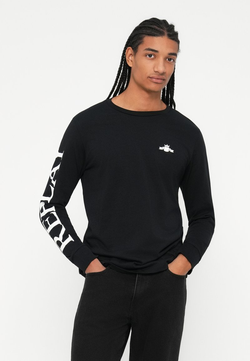 Schwarzes Langarm-T-Shirt mit rundem Halsausschnitt, gerippten Bündchen und weißem "REPUBLIC"-Text auf dem linken Ärmel. Dezentes Logo auf der Brust.