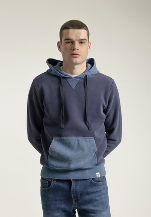 Sudadera de color azul marino con una capucha forrada en un tono de azul más claro y un bolsillo tipo parche. Fabricada con un tejido texturizado, cuenta con un diseño en V y cordones.