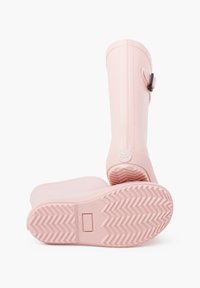 Des bottes de pluie en caoutchouc roses présentent une finition lisse, des rainures verticales, une boucle sur le côté et une semelle texturée avec des motifs en zigzag.