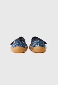 Blauwe stoffen instappers met een textuurpatroon en bruine rubberen zolen. Voorzien van een klittenbandsluiting en accentdetails.