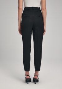 Gepersonaliseerde zwarte broek met een slim fit, voorzien van twee achterzakken, een gladde textuur en een hoge taille.