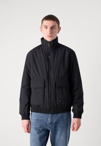 Jachetă bomber neagră cu guler înalt, închidere cu fermoar, două buzunare frontale, manșete și tiv din tricot. Fabricată dintr-un material neted, texturat.