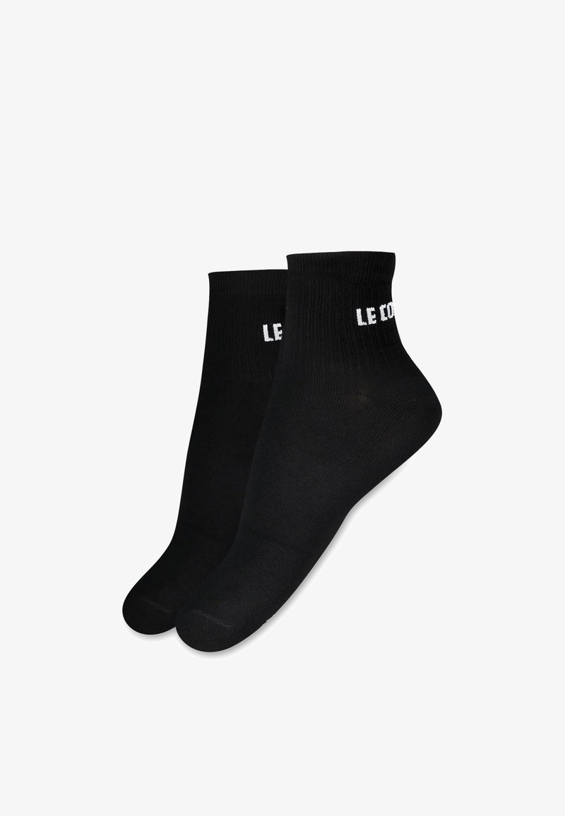 Calcetines de algodón negros hasta el tobillo con textura acanalada y la marca blanca "LE COQ" en el puño. Forma de puntera estándar con costuras reforzadas.