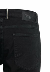 Sorte denim jeans med et lædermærke syet på taljen, to baglommer og standard syning.