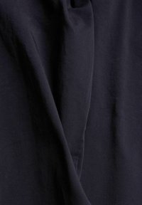 Tissu bleu foncé avec des plis doux et une légère texture, montrant les détails en gros plan du tissage du matériau.