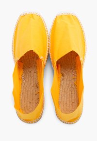 Žluté plátěné espadrilky s pletenou juta vnitřní podrá�žkou, otevřený design vpředu a bílým prošíváním kolem okrajů.