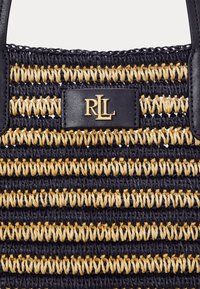 Auduma soma ar pārmaiņus tumši zilu un dabīgu šķiedru, ar melnu ādas akcentu, uz kura redzams zelta "RLL" logo. Rūpīgi norakstīts raksts un izturīgs dizains.