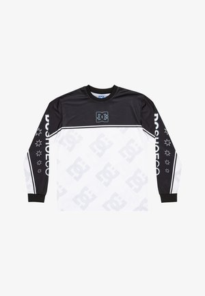 Chemise à manches longues présentant un haut noir avec une partie inférieure blanche, logo DC, motif d'étoiles sur les manches et poignets côtelés contrastés.