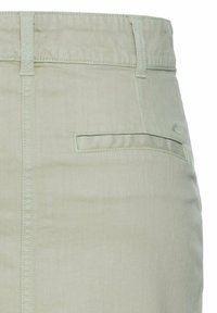 Hellgrüner Baumwollrock mit einem Taillenbund, Gürtelschlaufen und einer einzelnen Gesäßtasche mit Knopfverschluss. Sanfte Textur.