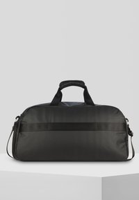 Bolsa de deporte negra con un acabado mate suave, dobles asas, correa de hombro ajustable y una franja texturizada horizontal en la parte delantera.