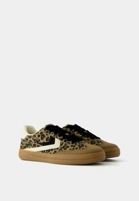 Leopard-print sneakers with a tan suede body, white leather accents, black laces, and a textured rubber sole. Low-profile design.