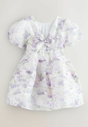 Balta suknelė su violetinės spalvos gėlių raštu, pūstomis rankovėmis, V formos iškirpte ir lankelio akcentu juosmens srityje, pasižyminti surinkta tekstūra ir sluoksniuota sijonu.