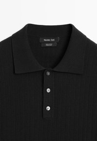 Polo noir en coton côtelé avec trois boutons et un col à rabat, étiqueté Massimo Dutti, fabriqué en Chine.