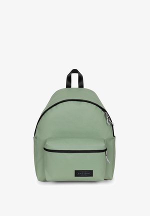 Backpack in light green fabric with a rounded shape, black zipper accents, a front pocket, and a top handle for carrying.