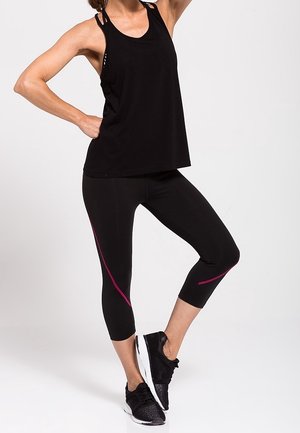 Débardeur de sport noir avec des bretelles fines, associé à un legging capri noir avec un accent rose. Des chaussures de sport noires complètent la tenue.