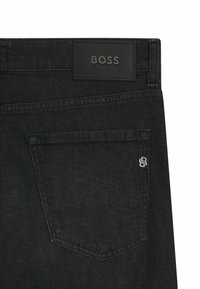 Jeans in denim nero con una patch in pelle testurizzata con il logo BOSS, dotati di una tasca posteriore con un logo B ricamato e dettagli di cucitura sottili.