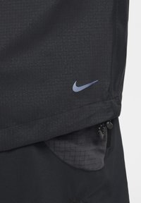 Mustat urheiluShortsit, joissa on tekstuurin omaava kangas, vetskari sivutasku ja pieni sininen Nike-logoe laidan. 