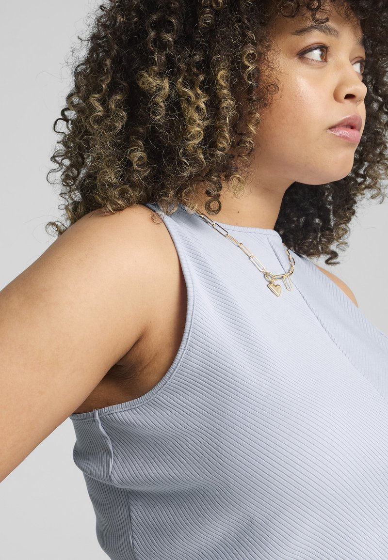 Débardeur côtelé bleu clair avec un col haut et sans manches. Présente une surface texturée et un détail sur la couture latérale.