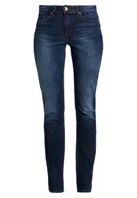 Jeans de mezclilla en un lavado azul oscuro con un corte ajustado. Cuenta con cinco bolsillos, un cierre de botón y un desvanecimiento mínimo. Textura resistente.