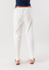 Pantaloni bianchi in cotone leggeri con vita elastica, dal taglio rilassato, caratterizzati da una texture liscia e un design a gamba affusolata.