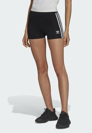 Pantalones cortos deportivos negros con tres rayas verticales blancas a cada lado, que presentan un logo de Adidas. La tela parece suave y ajustada.