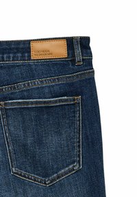 Vaqueros de mezclilla azul oscuro con una etiqueta de cuero que presenta "VERO MODA" en la parte trasera, destacando un diseño clásico de bolsillo y detalles visibles de costura.