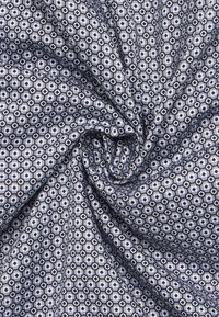 Tessuto con un motivo esagonale ripetuto in tonalità blu navy e bianco, caratterizzato da una texture liscia e una caduta leggera.