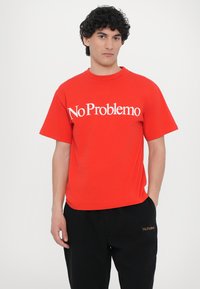 Rotes Baumwoll-T-Shirt mit "No Problemo" in großen weißen Buchstaben auf der Brust bedruckt. Kurze Ärmel und Rundhalsausschnitt.