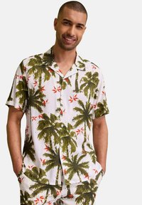 Camicetta a maniche corte in tessuto bianco con stampe di palme verdi e fiori rossi, bottoni e vestibilità rilassata, abbinata a pantaloni corti coordinati.