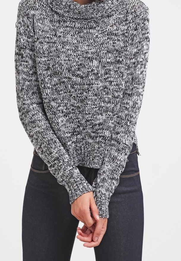 Maglione lavorato a maglia con un motivo mélange bianco e nero, colletto a cowl, maniche lunghe e orlo a costine, con mani visibili vicino alla vita.