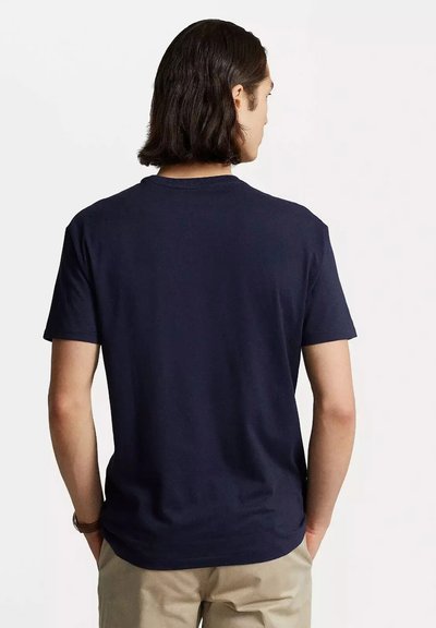 Maglietta in cotone blu navy con colletto a girocollo e maniche corte, caratterizzata da una texture liscia e un design semplice, vista dal retro.