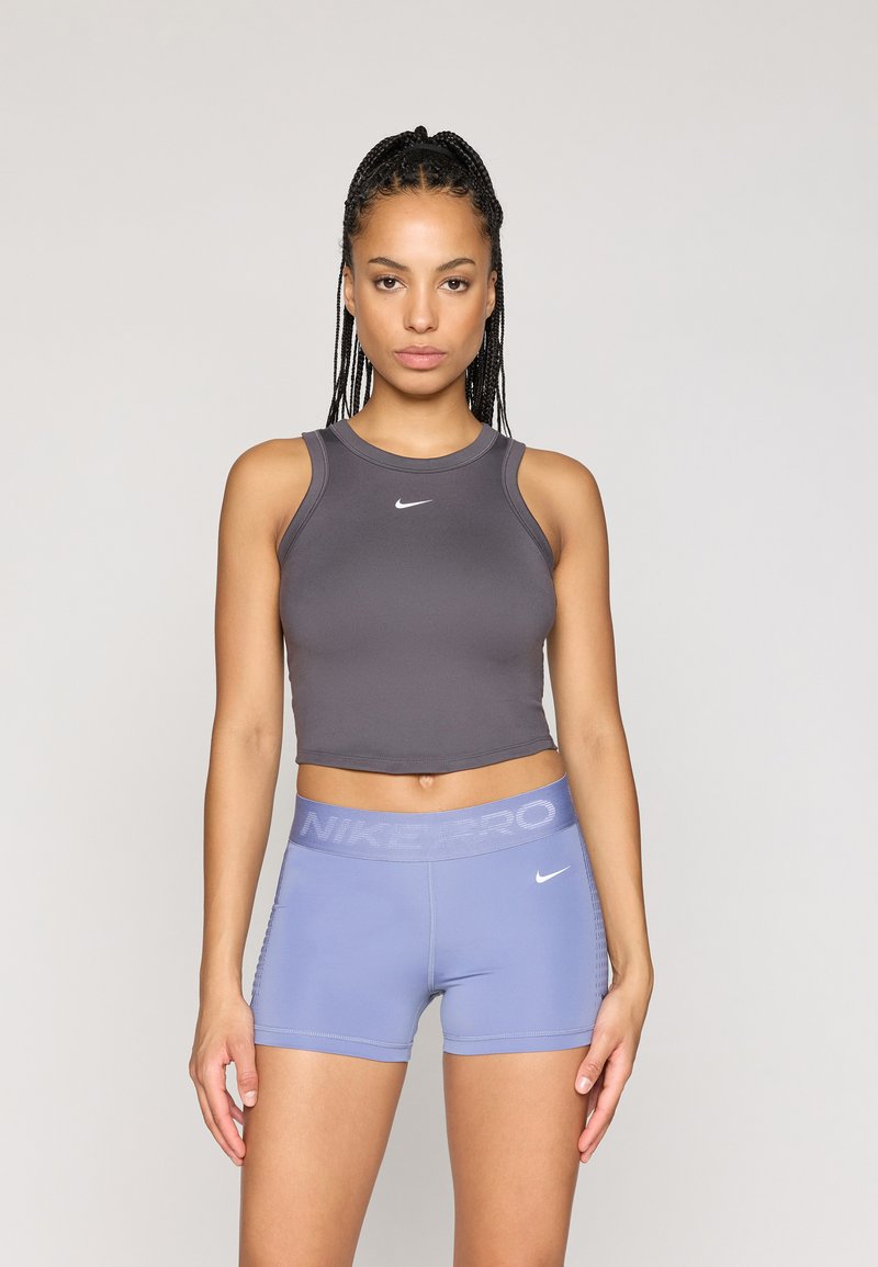 Haut de sport gris cropped avec un col rond et le logo Nike, associé à un short bleu clair avec une taille et un logo "NIKE PRO".