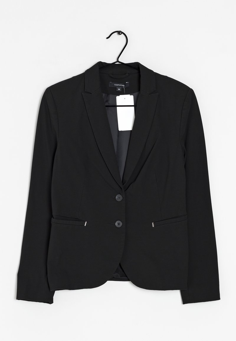 Blazer noir pour femme, tailleur, avec deux boutons et poches avant, accroché à un cintre noir avec une étiquette de prix blanche attachée.