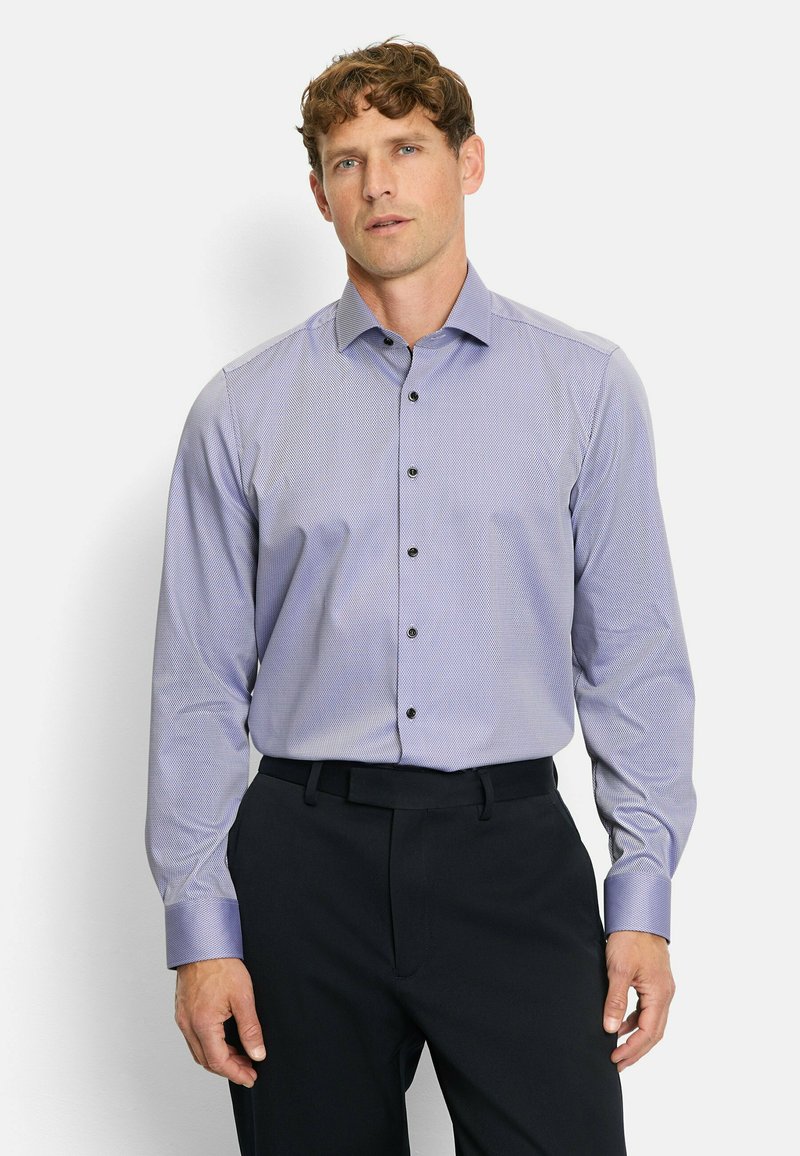 Light purple long-sleeve shirt with a dotted pattern, button placket with dark buttons, and contrasting collar details. Paired with dark trousers.
