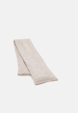 Écharpe en tricot beige clair, pliée à plat sur une surface blanche.