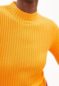 Pull en maille côtelée de couleur jaune vif avec un col montant. Présente une coupe ajustée et une texture douce. Sans accents ni éléments métalliques visibles.