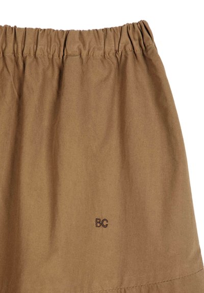 Tissu marron avec taille élastique froncée et petites lettres noires brodées "BG" près du bord inférieur sur un fond uni.