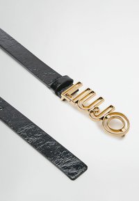 Ceinture en simili cuir noir avec une boucle en métal doré brillante portant le nom de la marque "LIU JO" en lettres stylisées et un accent circulaire.
